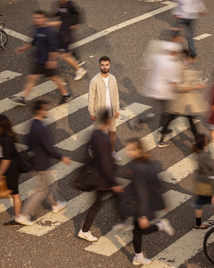 A crossing at rush hour, everyone around me blurred by the exposure, me standing still and looking back at the camera.